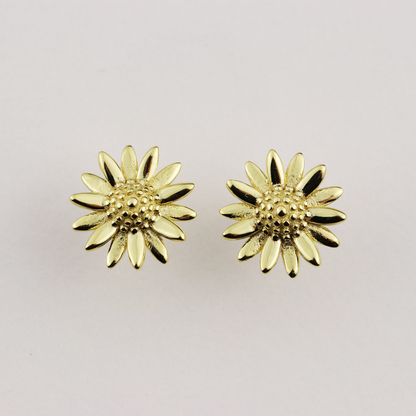 Gold sunflower-shaped earrings on a light gray background